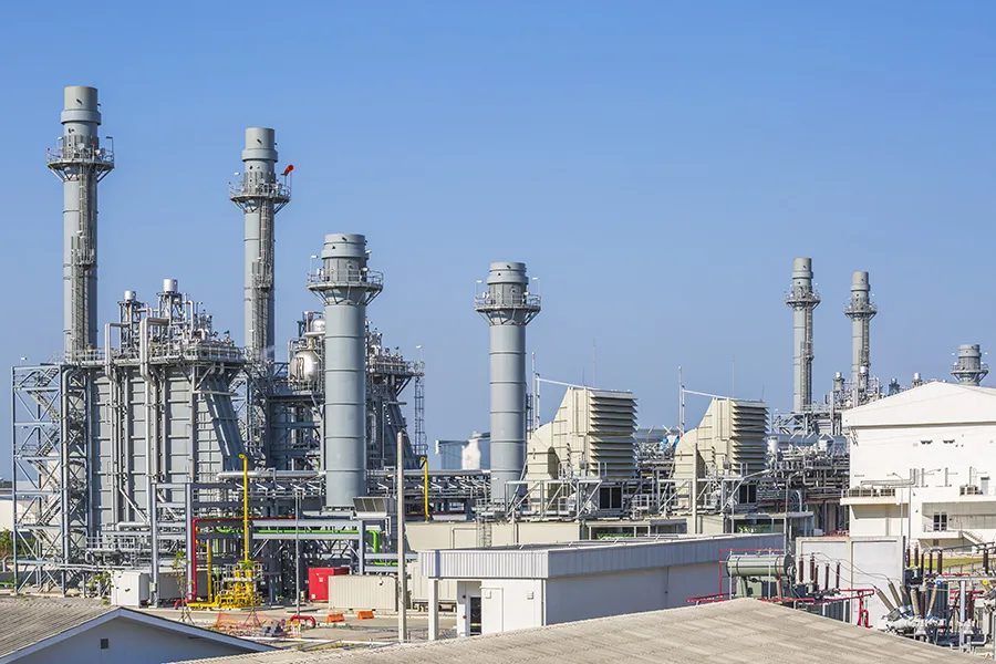 Gas-fired power plant with exhaust stacks under a clear sky